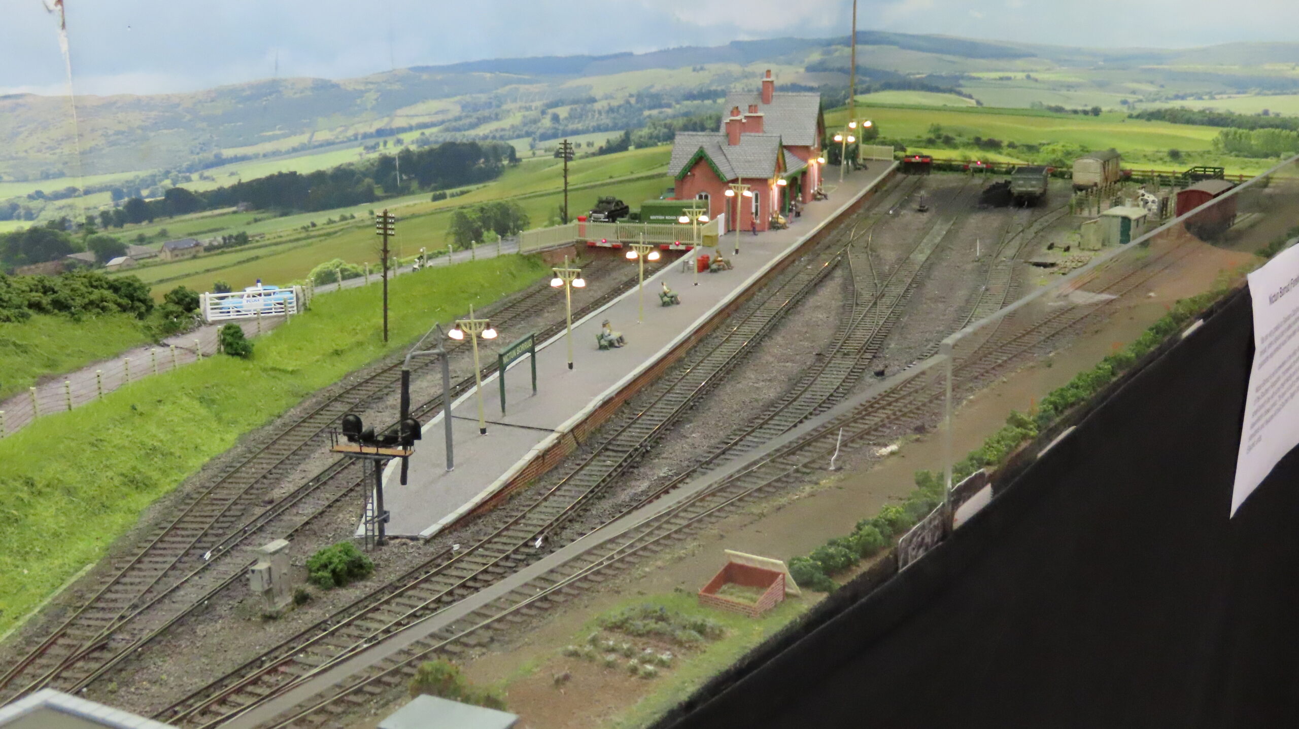 Image showing a small model railway layout with a platform and sidings in a green countryside setting.